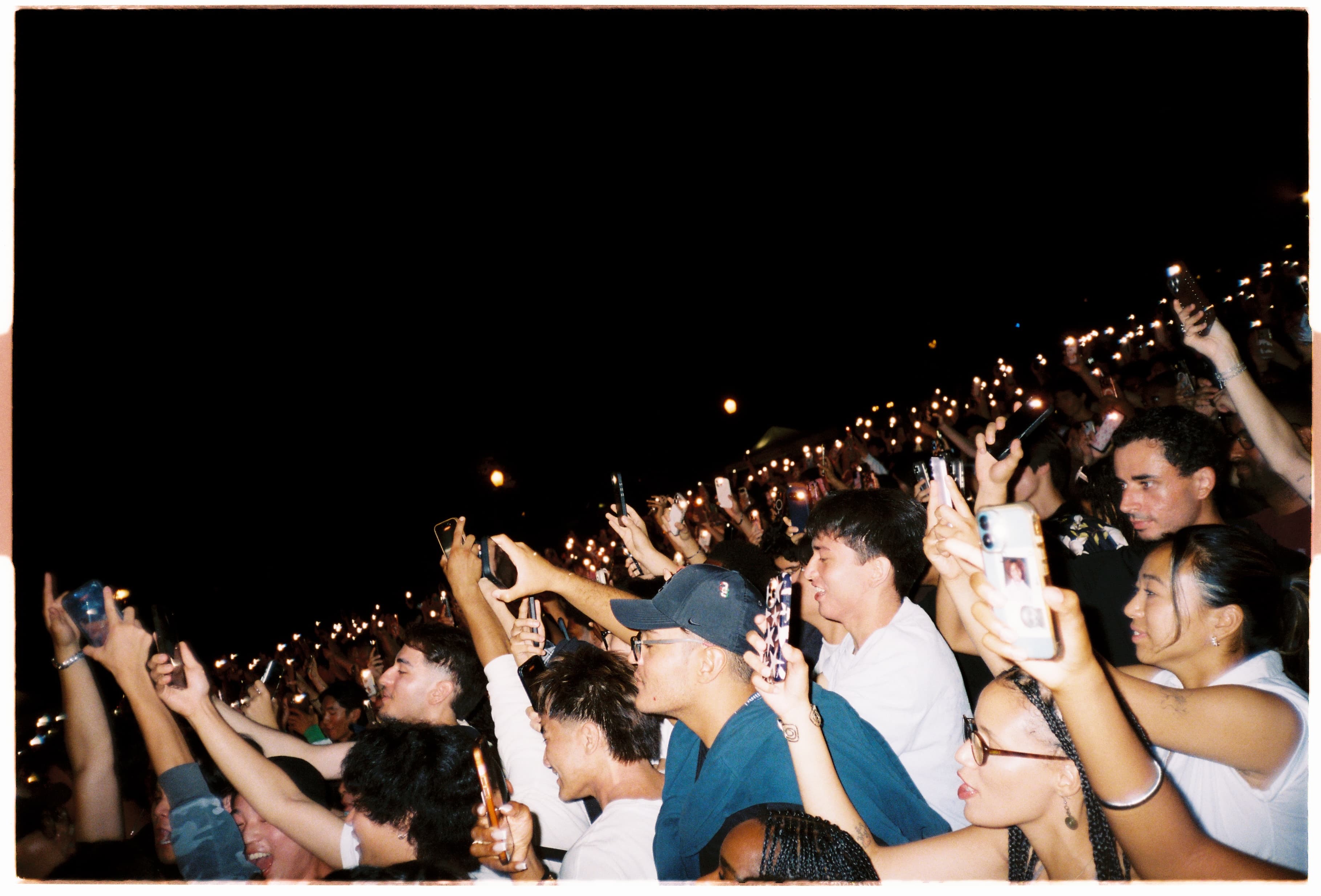 A sea of phone flashlights in the dark as the crowd films the show.